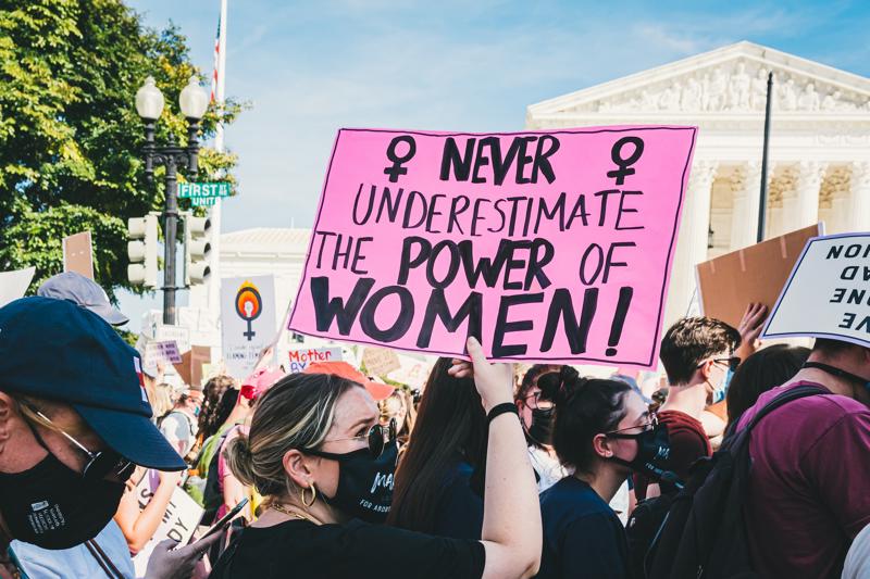 Women holding a sign saying "Never underestimate the power of women"