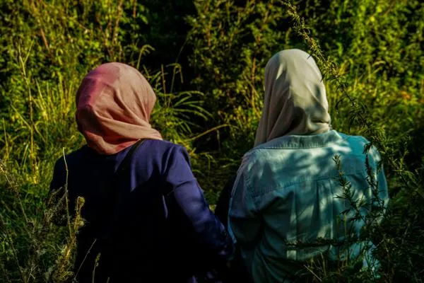 Two women standing in a field, pictured from behind