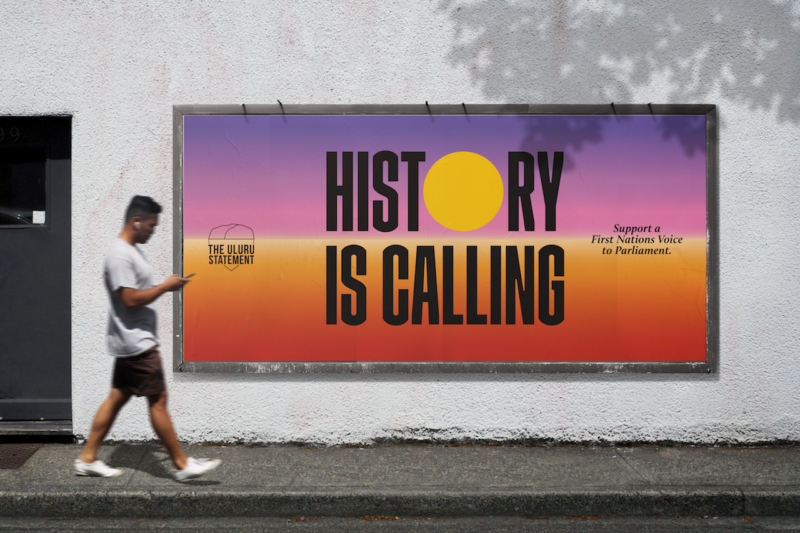 Image of a person walking past a campaign poster saying "history is calling"