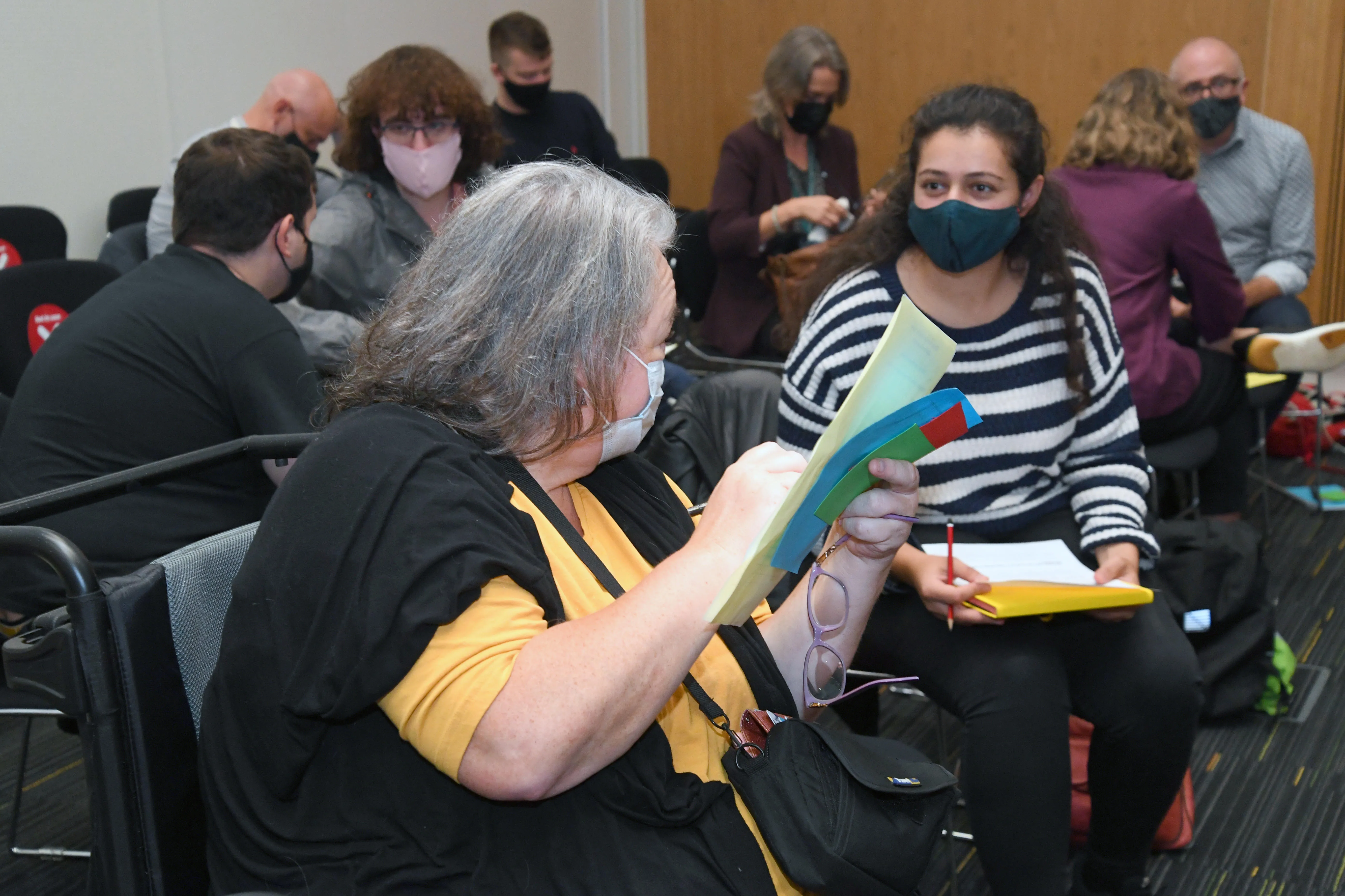 Two women discussing and writing policy ideas while wearing face masks