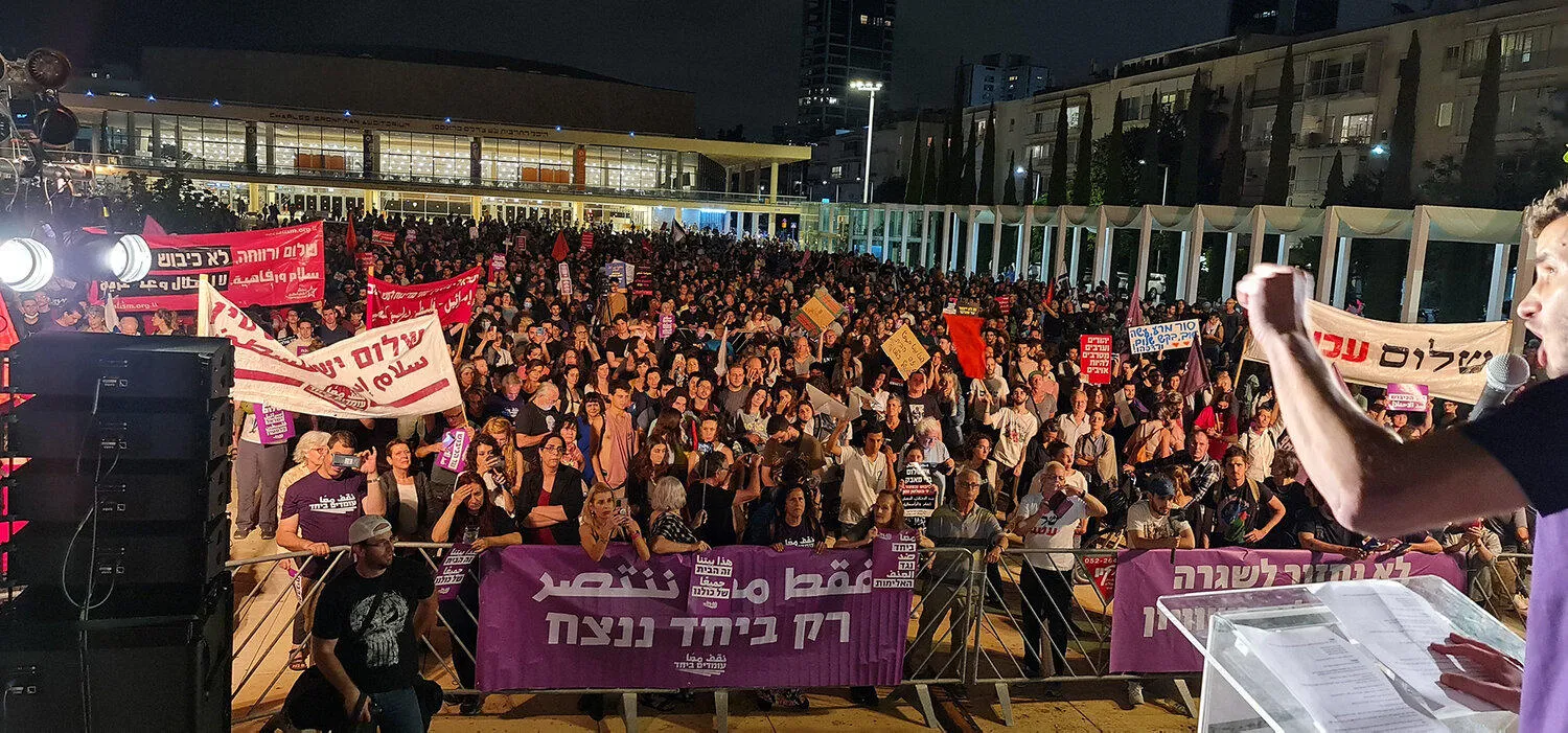 A view from the stage at the rally with hundreds of people holding banners and placards.