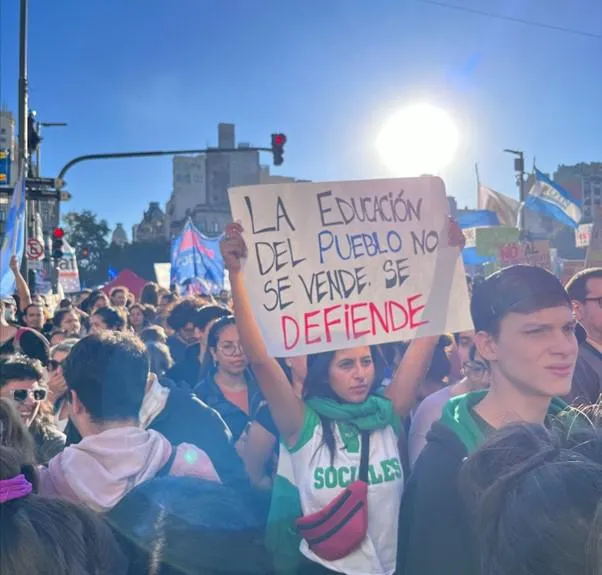 A woman in a protest holding a sign that says “The education of the nation is not for sale, it is to be defended”