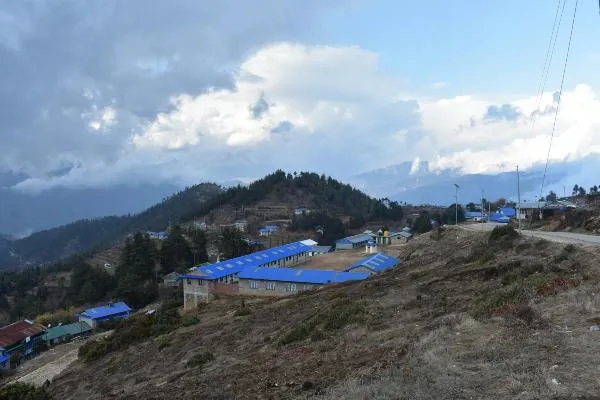 A village school on the hill with mountains in the background