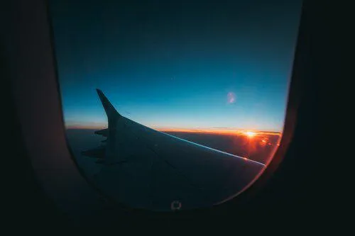 A sunrise over a wing tip seen at altitude from a commercial plane seat