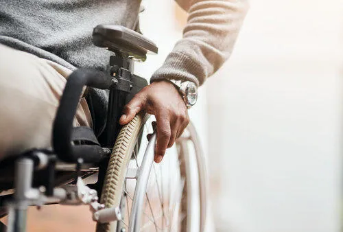 A wheelchair users hand resting on a wheel