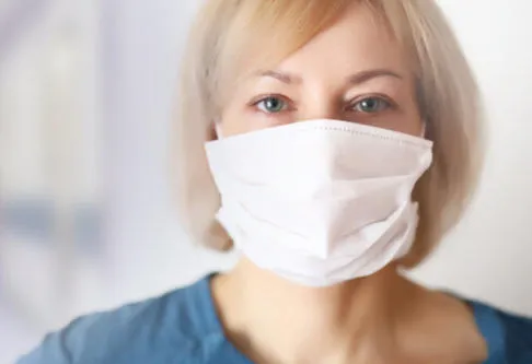 A person in a mask with illustrations of germs floating near them