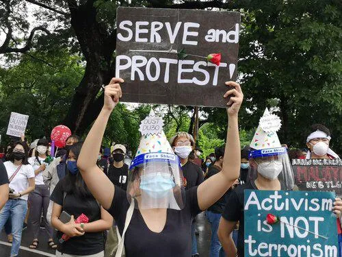 Demonstrators hold banners in the air one of which says "Serve and protest"