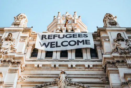 A beautiful old building with a "Refugees Welcome" banner hanging from it