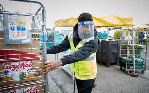 A photo of Marcus Rashford moving a food cage at an outside depot