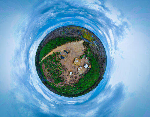 A swirling 360 degree photo of a group of huts in a clearing