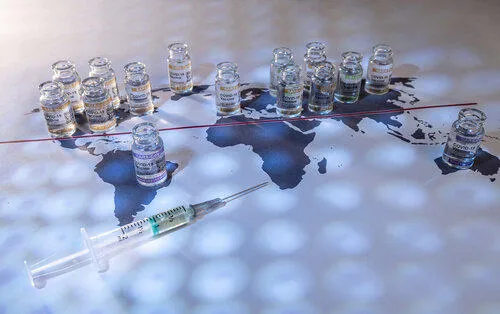 Bottles of Covid vaccines laid out over a map of the world