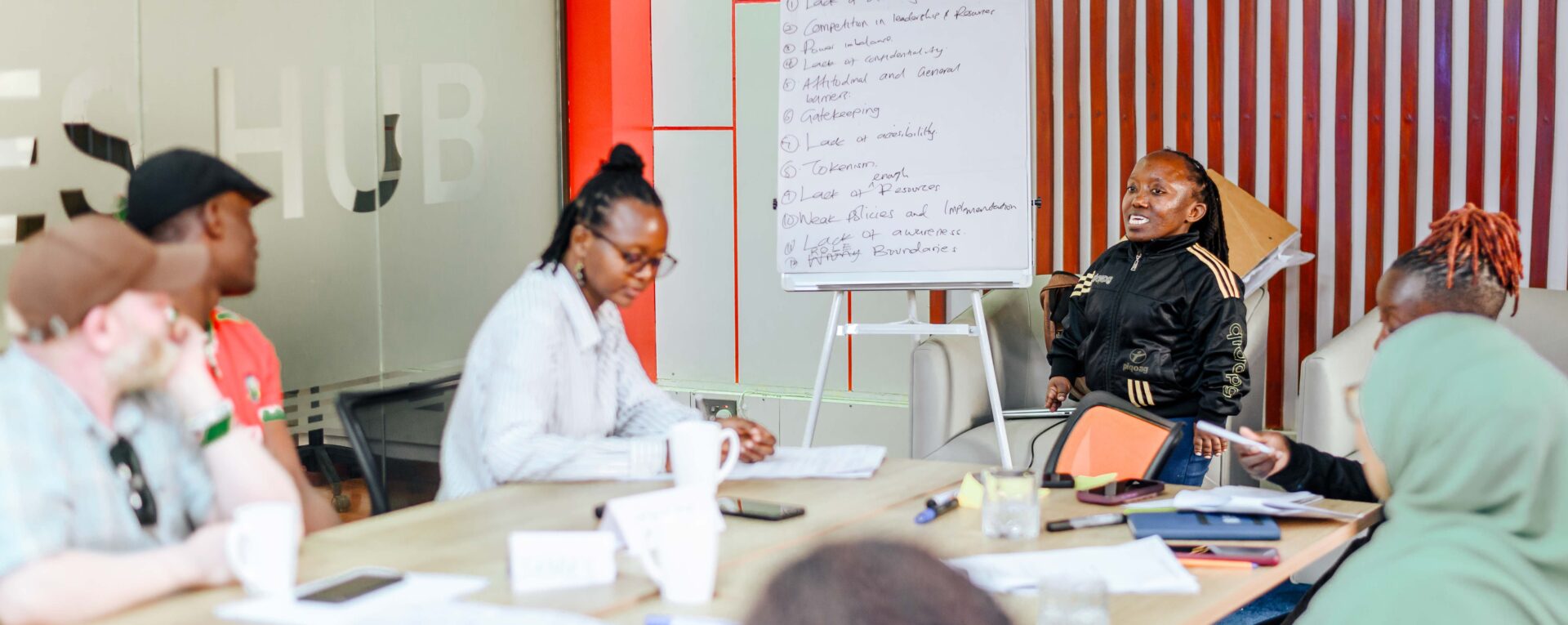 A person presenting to people seated around a table