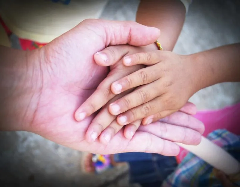 Adult holding child's hands