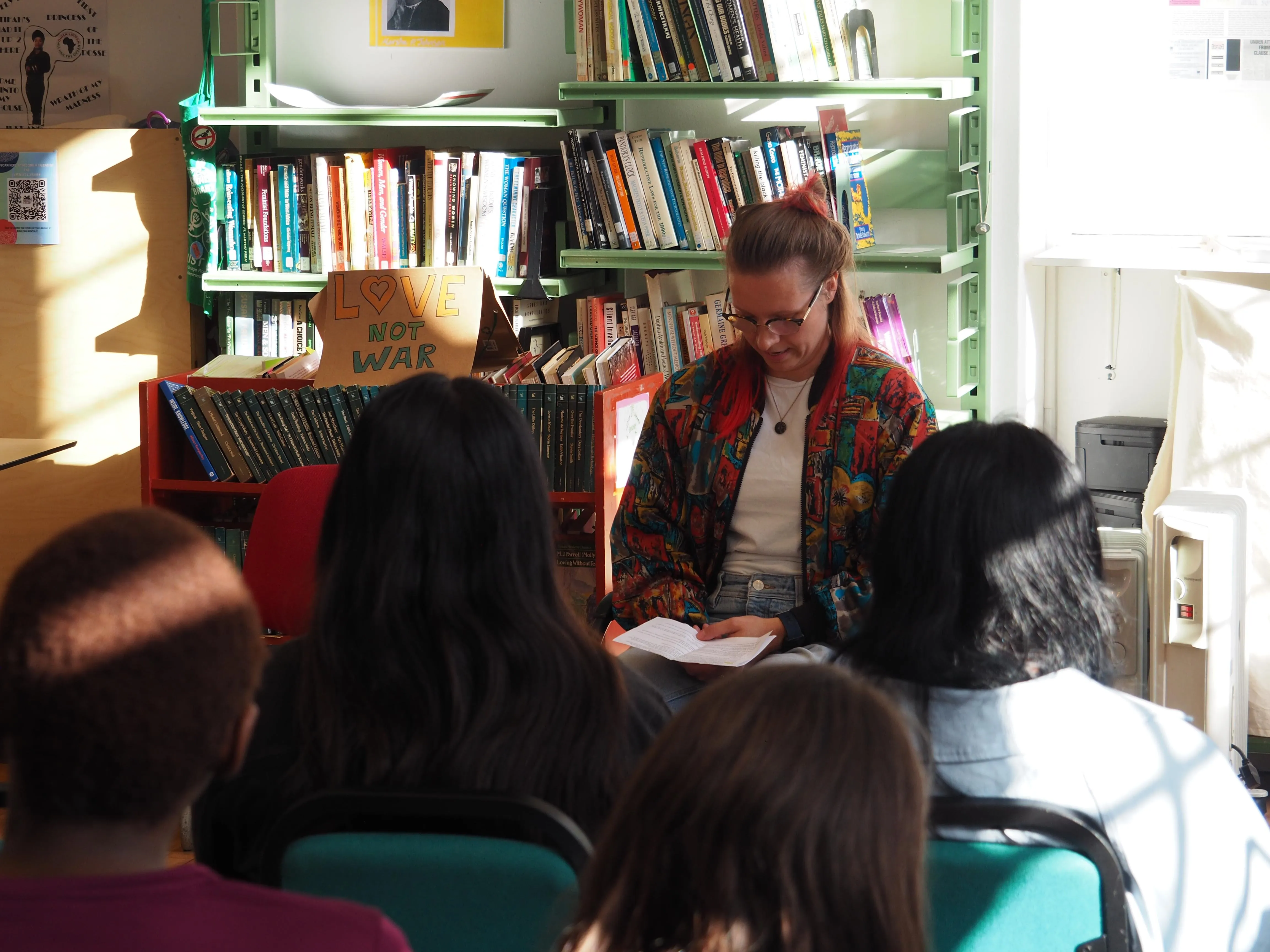 A woman in a colourful jacket presenting in front of an audience