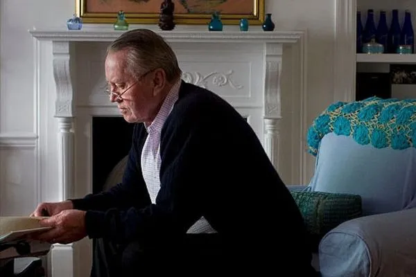 A man sitting in an armchair reading a book