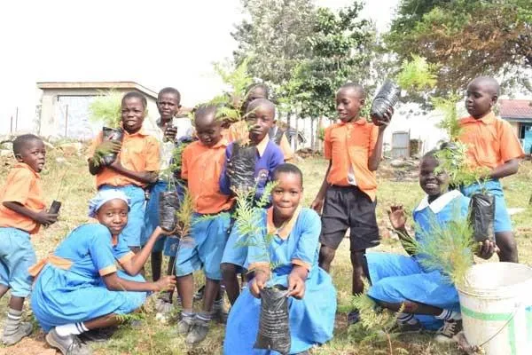 Group of school children holding potted plants 