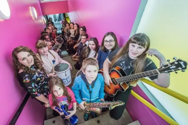 A group of children standing on stairs holding instruments 